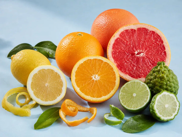 Sliced lemon, orange, grapefruit, lime and bergamot with green leaves on a pale sky-blue background