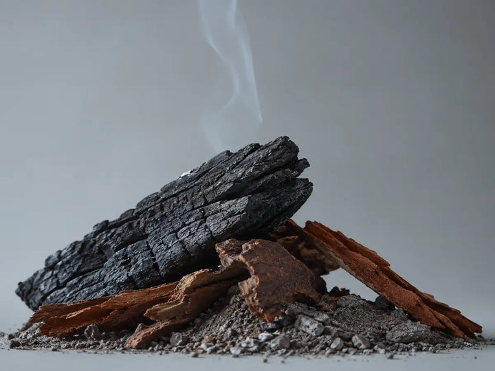 Charred wood, cedar bark and grey ash representing a smoky perfume note
