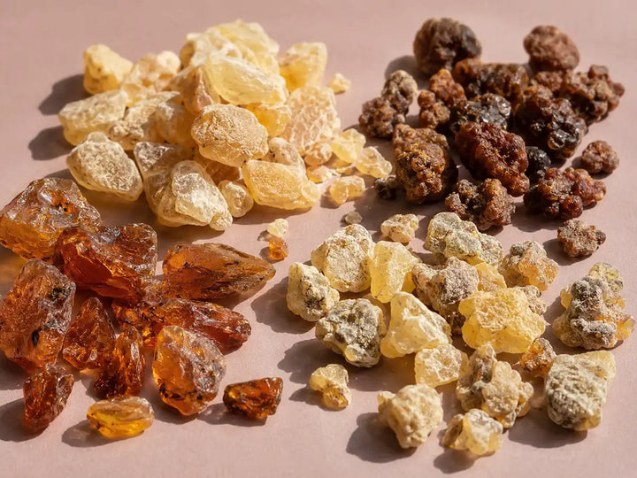 Benzoin, myrrh and incense resins arranged on a pale dusty rose background