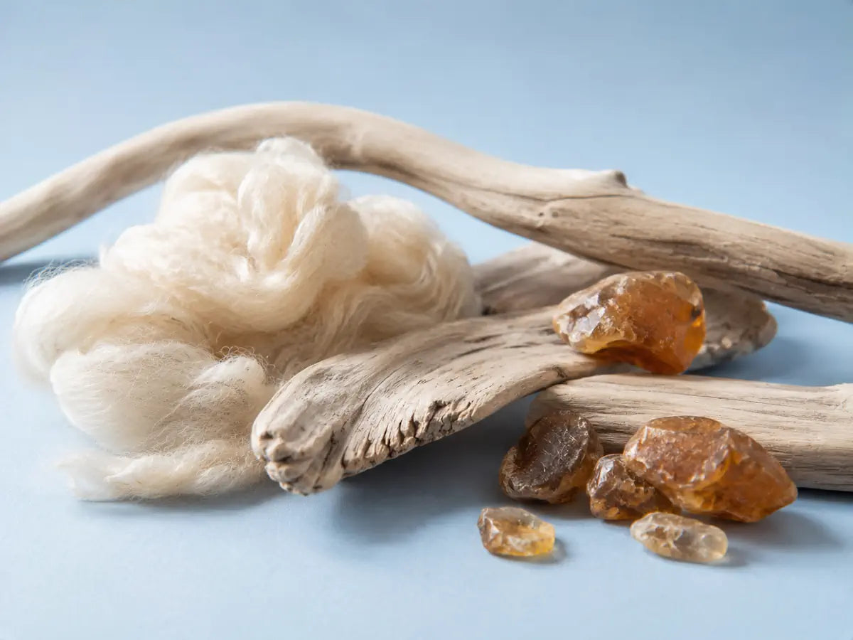 Pale wood, soft natural fibres and warm amber-toned stones representing the character of Cashmeran