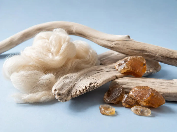 Pale wood, soft natural fibres and warm amber-toned stones representing the character of Cashmeran