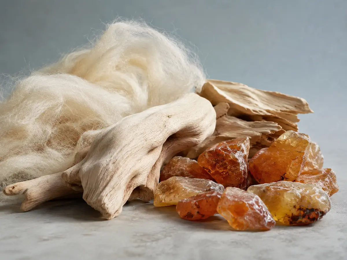 Pale wood, soft fibres and amber-toned stones representing the warm character of cashmere wood